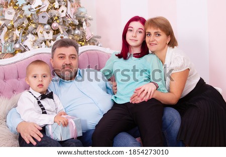 New Year's photo session of a family in which there is a boy with Down syndrome, a disabled child, inclusion, a happy family at the Christmas tree.
