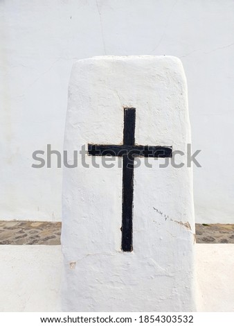 A cross made of black wood on the wall of a church