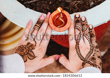 Close up shot of Diya lamp with traditional mahendi design in female hands. During celebration of Hindu festival Diwali also known as Deepavali