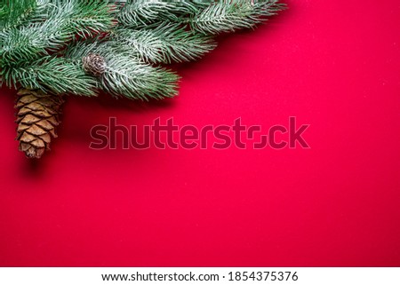 Red New Year or Christmas background with fir branch covered with snow and Christmas decor. Top view.