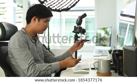A man freelance photographer is working on his project at office desk with multiple computers.