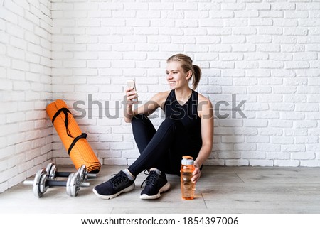 Young smiling fitness woman doing selfie after workout sitting at the floor