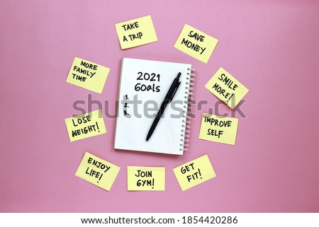 New Year Resolution Goal List 2021 with notebook written in handwriting about plan listing of new year goals and resolutions on pink background