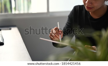 Cropped shot of graphic designer or photographer hand drawing at portable tablet computer.