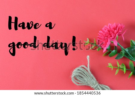Top view of flower, rope on a red background written with text HAVE A GOOD DAY!. Motivational concept. 