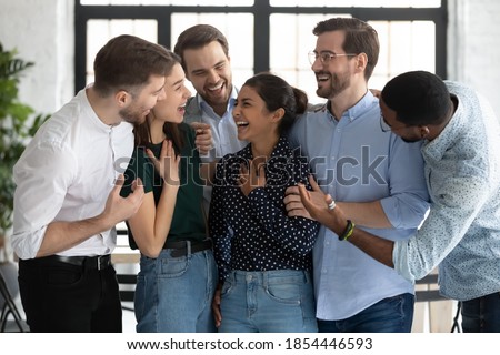 Fellowship. Happy diverse young friends multiethnic coworkers business partners students hugging talking laughing in office university hallway greeting indian female mate with achievement luck success Royalty-Free Stock Photo #1854446593