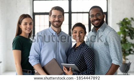 Portrait of successful diverse international business team friendly group of four coworkers capable reliable professional specialists posing at office standing close together smiling looking at camera Royalty-Free Stock Photo #1854447892