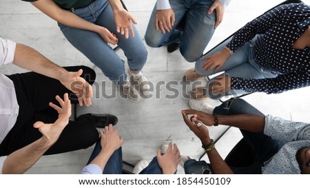 Psychological assistance. Close up of diverse group of unknown young people sitting in narrow circle on mental therapy session speaking by turn sharing personal problem listening understanding helping Royalty-Free Stock Photo #1854450109