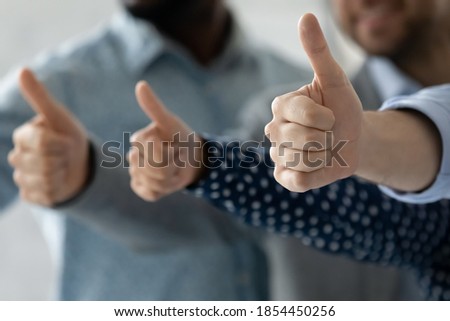Perfect choice for everyone. Close up of multiethnic men and women hands raised in thumbs up gesture approving recommending best contract or loan terms conditions, qualified goods service assistance Royalty-Free Stock Photo #1854450256