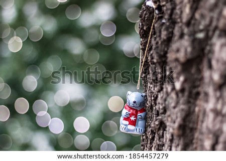 New Year toy-rat, hanging on a tree trunk on the background of bokeh Christmas lights