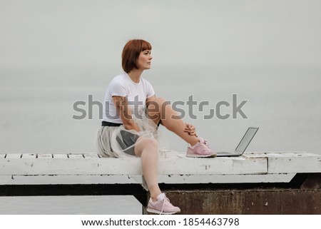 Attractive woman frelancer working on modern laptop while sitting on seafront