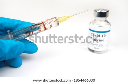 Doctor holding a syringe and a vaccine / hands of a doctor preparing a dose for the vaccination campaign.covid-19 coronavirus vaccination.