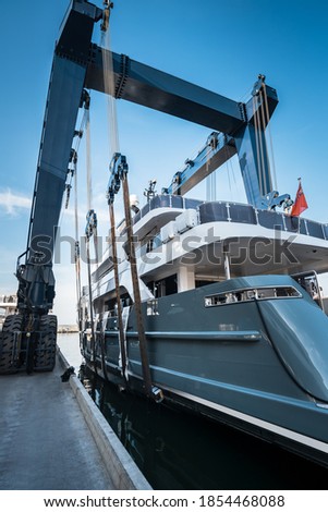 New beautiful superyacht being launched or hauled out by a crane at shipyard on a day with blue sky Royalty-Free Stock Photo #1854468088