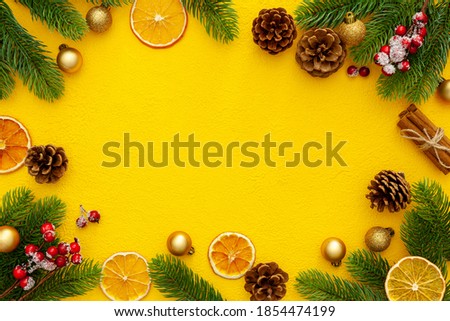 Spruce branch, cones and toys decoration on christmas or new year on yellow background
