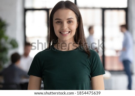 Headshot portrait profile picture of happy young woman employee student standing in office college university at workday looking at camera satisfied proud of being staff member getting good education