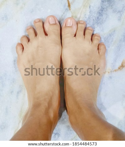woman bare feet standing on marble texture.