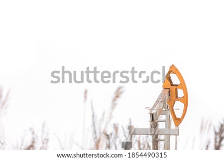 The oil pump jack is on the white winter landscape in Russia. Winter oilfield 