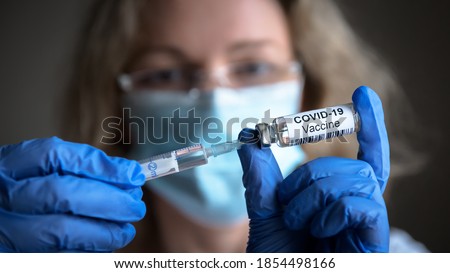 COVID-19 vaccine in researcher hands, female doctor's holds syringe and bottle with vaccine for coronavirus cure. Concept of corona virus treatment, injection, shot and clinical trial during pandemic Royalty-Free Stock Photo #1854498166
