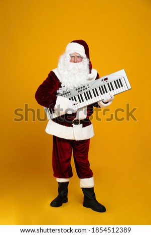 Santa Claus with synthesizer on yellow background. Christmas music