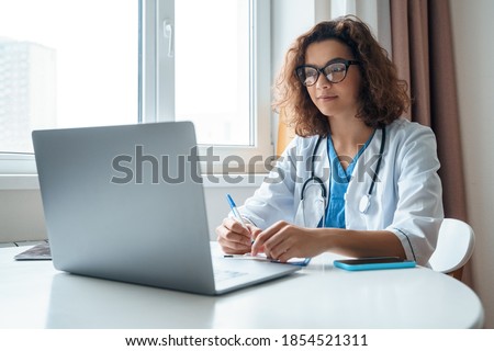 Attractive female doctor make online video call consult patient on laptop. Medical assistant young woman therapist videoconferencing to web camera. Telemedicine concept. Online doctor appointment. Royalty-Free Stock Photo #1854521311