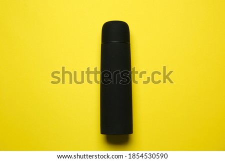 Black thermos on yellow background, top view