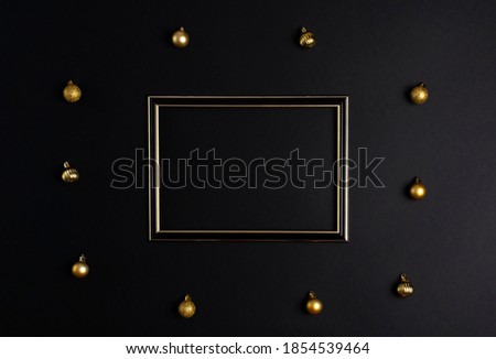 On a black background, a photo frame with a place for text, around there are golden Christmas balls