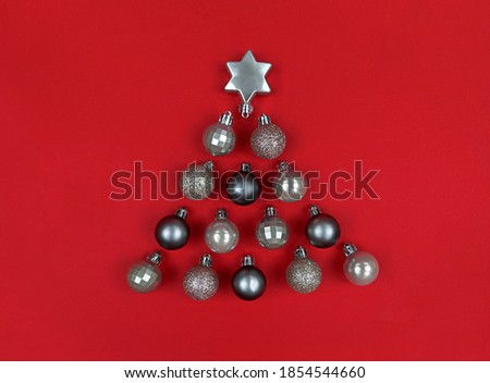 Christmas tree shape made with decor baubles on a red paper.