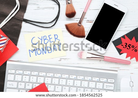Inscription Cyber Monday with makeup brushes, phone and keyboard on wooden background