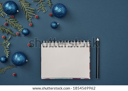 New Year's decor and a notebook in the center on a blue background. Christmas decoration. Copy space, flat lay, mock up, top view