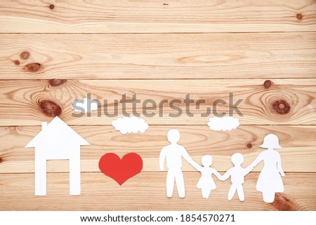 Family and house figures with red heart on wooden table