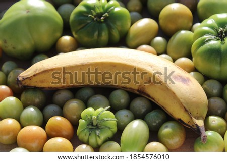 unripe tomatoes that ripen faster with a banana Royalty-Free Stock Photo #1854576010