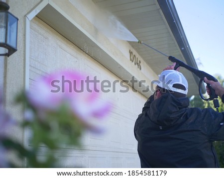 Man Power Washing Side Of House Cleaning House With High Pressure Washer Royalty-Free Stock Photo #1854581179