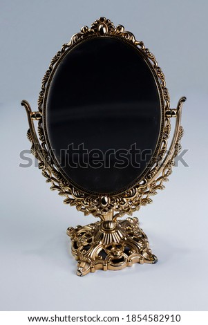 Mirror standing on a white background, with gold color embroidered edges