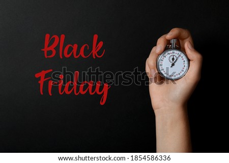 Phrase Black Friday and woman holding timer against dark background, closeup