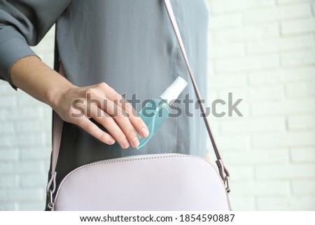 Woman putting hand sanitizer in purse indoors, closeup. Personal hygiene during COVID-19 pandemic Royalty-Free Stock Photo #1854590887