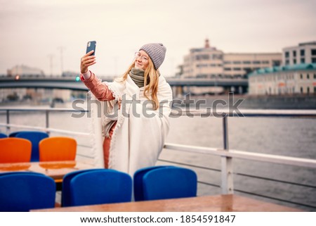 Young woman in glasses traveler in a hat and jacket making a selfie in Moscow on a pleasure boat on the river in center