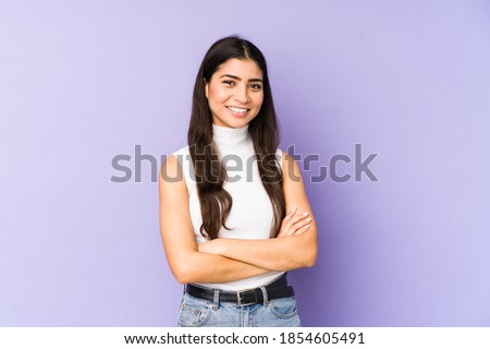 Young indian woman isolated on purple background who feels confident, crossing arms with determination.