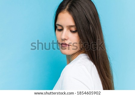 Young caucasian girl face closeup isolated in a blue background