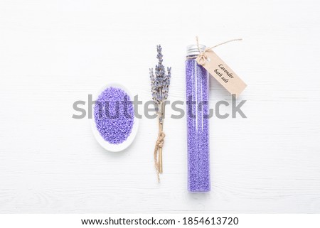 Lavender bath solt in the plastic tube and dried lavender flowers on the white background.