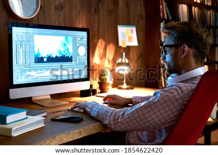 Male videographer editor film maker using pc computer editing video footage visual content working on pc at home office using post production video editing multimedia montage digital software concept.