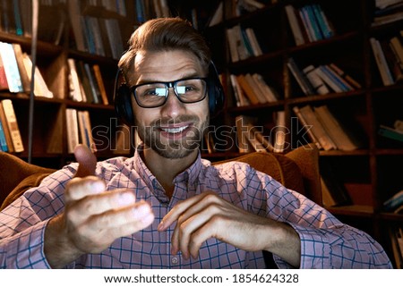 Happy young business man, student, remote teacher, distance tutor wearing headphones talking to cam conference video calling, giving webinar, online class, teaching or streaming, webcam view. Headshot Royalty-Free Stock Photo #1854624328