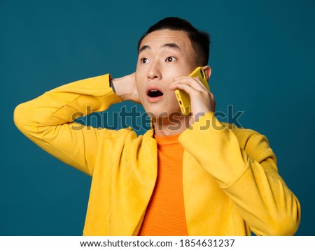 Surprised guy with a phone in his hands opened his mouth wide on a blue background
