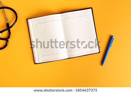 blank notepad, stethoscope and pen on bright orange background with place for text