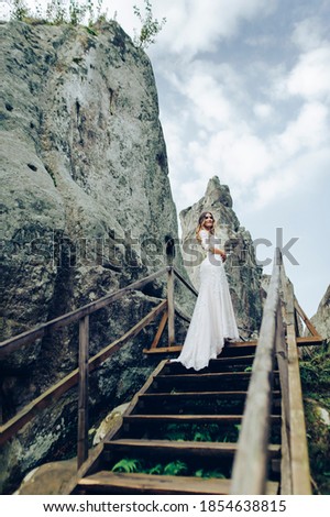 Incredible bride in exquisite wedding dress at sunrise in the mountains.