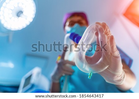 Female doctor puts oxygen mask to a patient. View from the eyes of a patient. Blurred background Royalty-Free Stock Photo #1854643417