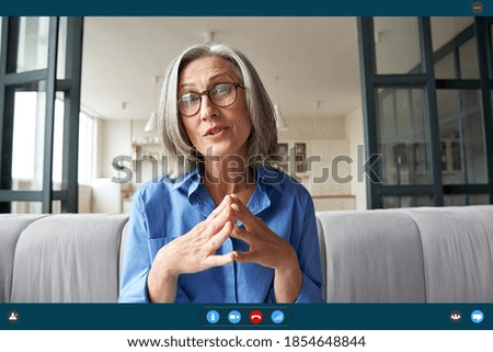 Senior mature old woman online teacher, remote tutor, distance coach talking to web cam virtual counseling conference video calling at home office. Web cam view. Videocall app screenshot screen view Royalty-Free Stock Photo #1854648844