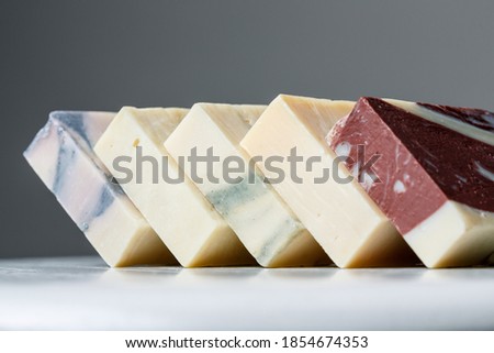 Natural handmade soap bars with different ingredients on a white wooden background. Organic skin care treatment concept 