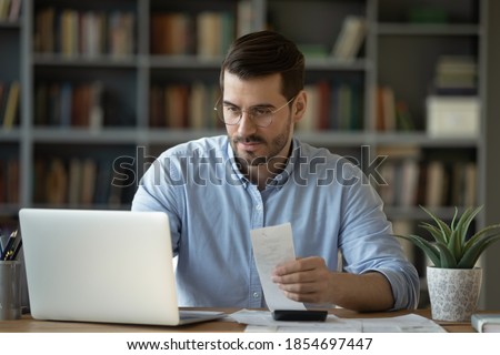 Personal finance application, budgeting software advertising, successful managing money concept. Accountant man employee sit at desk using laptop app make payments online, check expenses, do paperwork Royalty-Free Stock Photo #1854697447