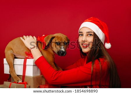 Happy girl with her Christmas present. Christmas tale. Favorite pet. Photo on a red background.