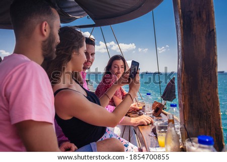 Friends on vacation taking selfies in front of the sea on a boat
